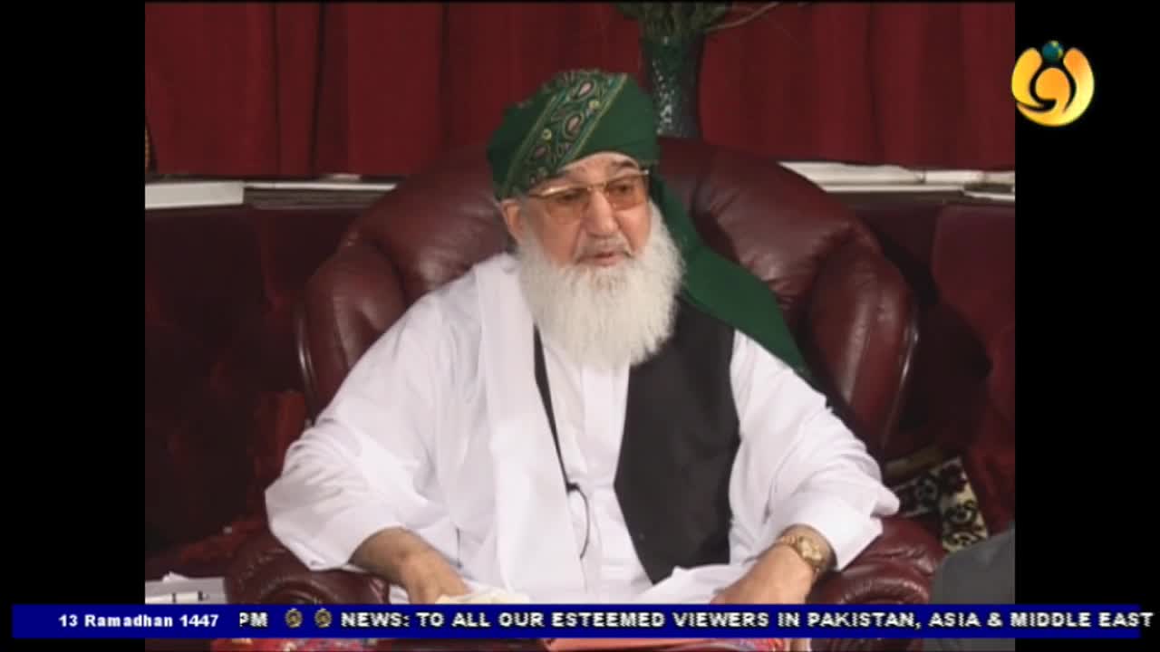 A man in a green turban and white robe speaks from a leather chair. A Noor TV chyron scrolls across the bottom of the screen.