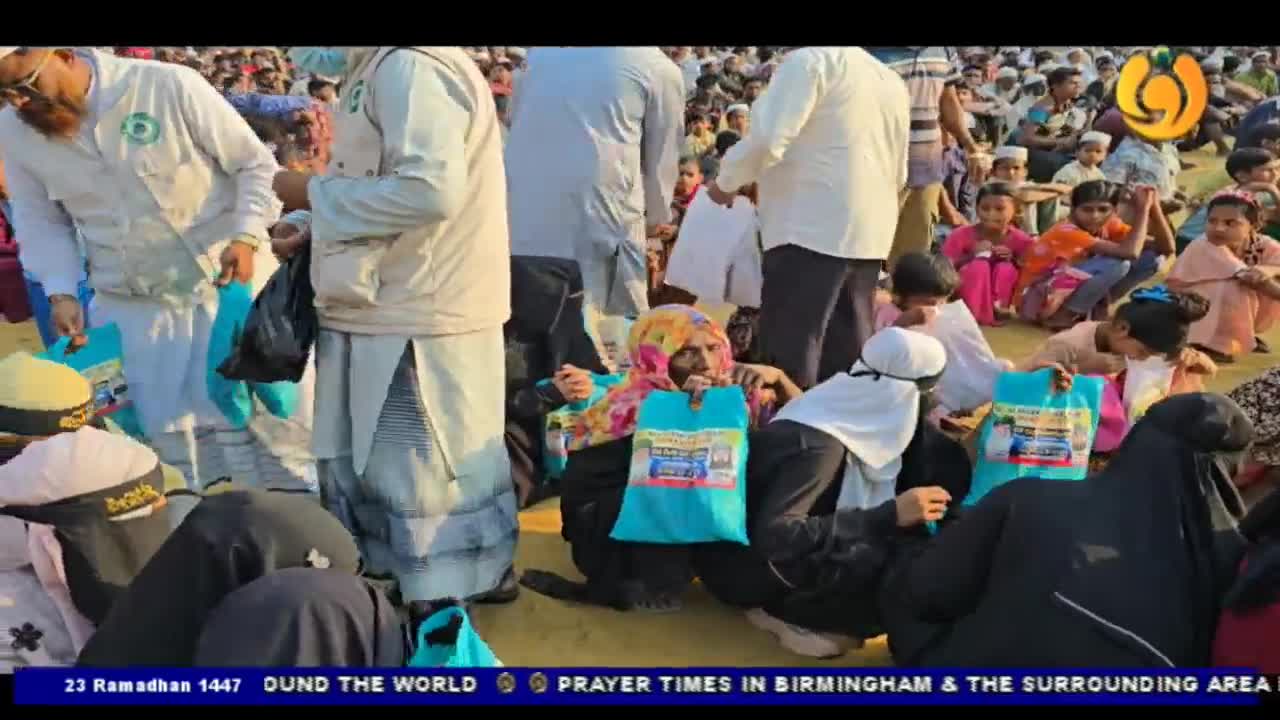 People are receiving bright blue bags from men in white vests. A woman in a colourful headscarf clutches her bag, looking towards the camera.