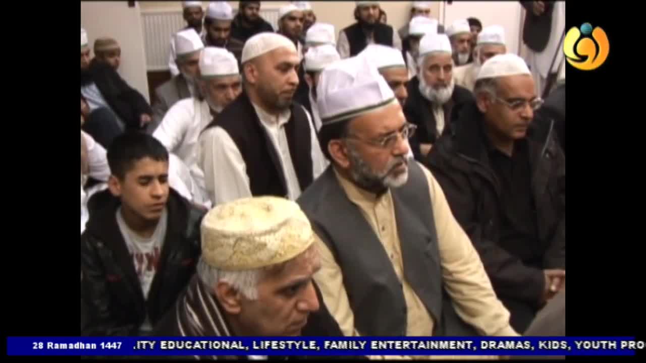 A group of men, some wearing white kufis, are seated, listening intently. A young boy in a black jacket sits among them, his gaze fixed forward. A group of men, some wearing white kufis, are seated, listening intently. A young boy in a black jacket sits among them, his gaze fixed forward.