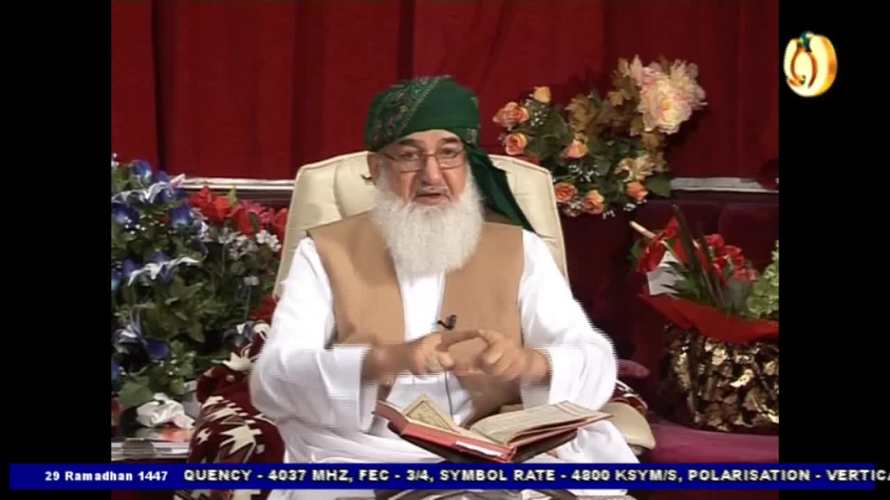 A man in a green turban and tan vest speaks, gesturing with his hands over an open book. The broadcast information at the bottom indicates this is from the UK on Noor TV. A man in a green turban and tan vest speaks, gesturing with his hands over an open book. The broadcast information at the bottom indicates this is from the UK on Noor TV.