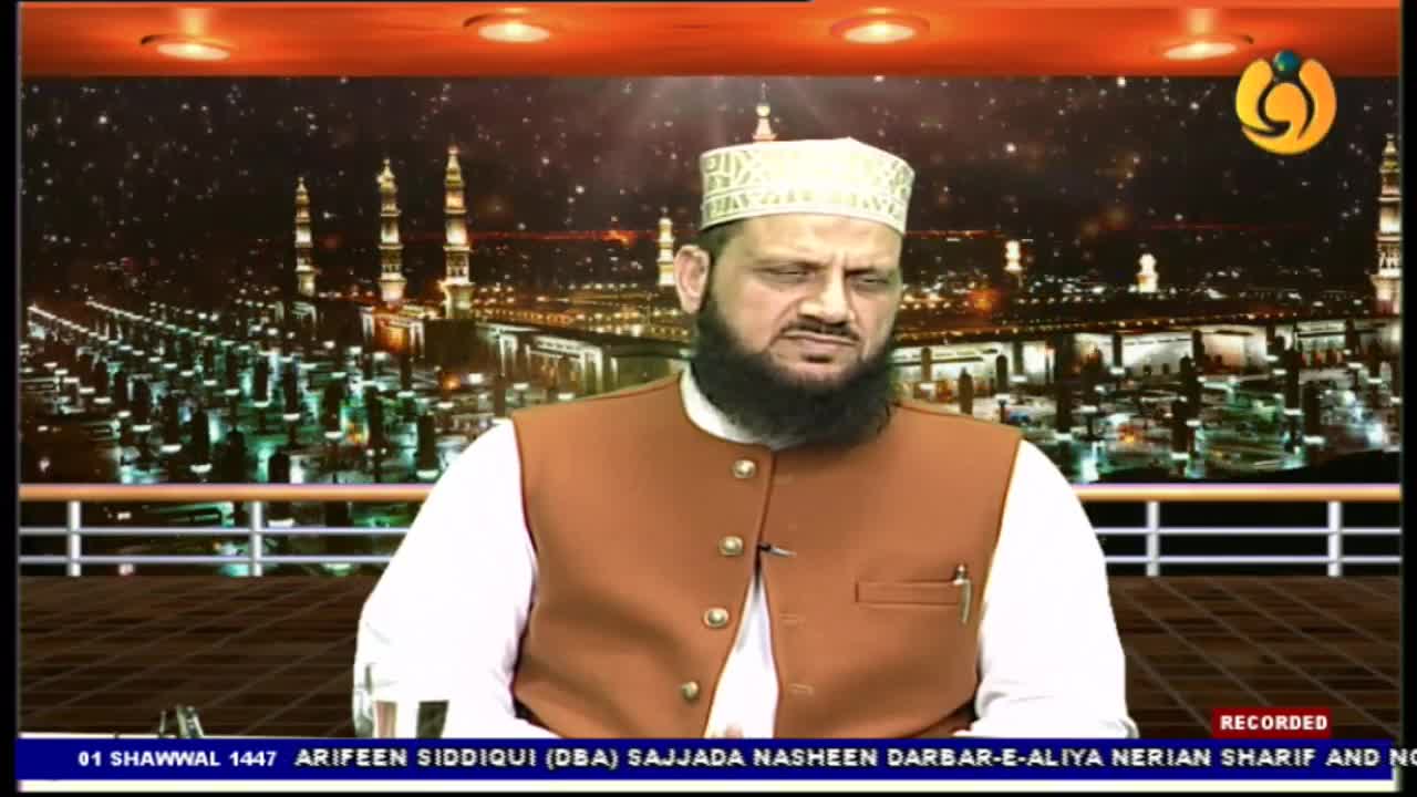 A man in a white shirt and brown vest sits with his head slightly bowed. Behind him, a nighttime cityscape with illuminated minarets stretches across the screen, suggesting a broadcast from Noor TV. A man in a white shirt and brown vest sits with his head slightly bowed. Behind him, a nighttime cityscape with illuminated minarets stretches across the screen, suggesting a broadcast from Noor TV.