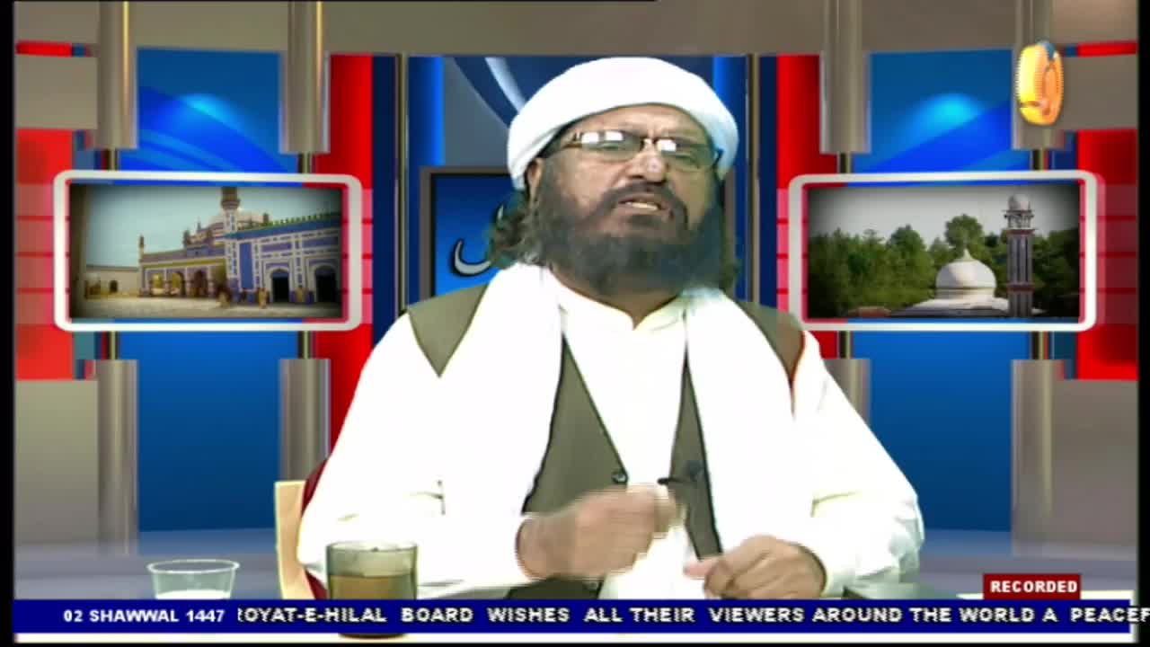 A man in a white turban and glasses speaks directly to the camera, gesturing with his right hand. On screens behind him, images of mosques are displayed. A man in a white turban and glasses speaks directly to the camera, gesturing with his right hand. On screens behind him, images of mosques are displayed.