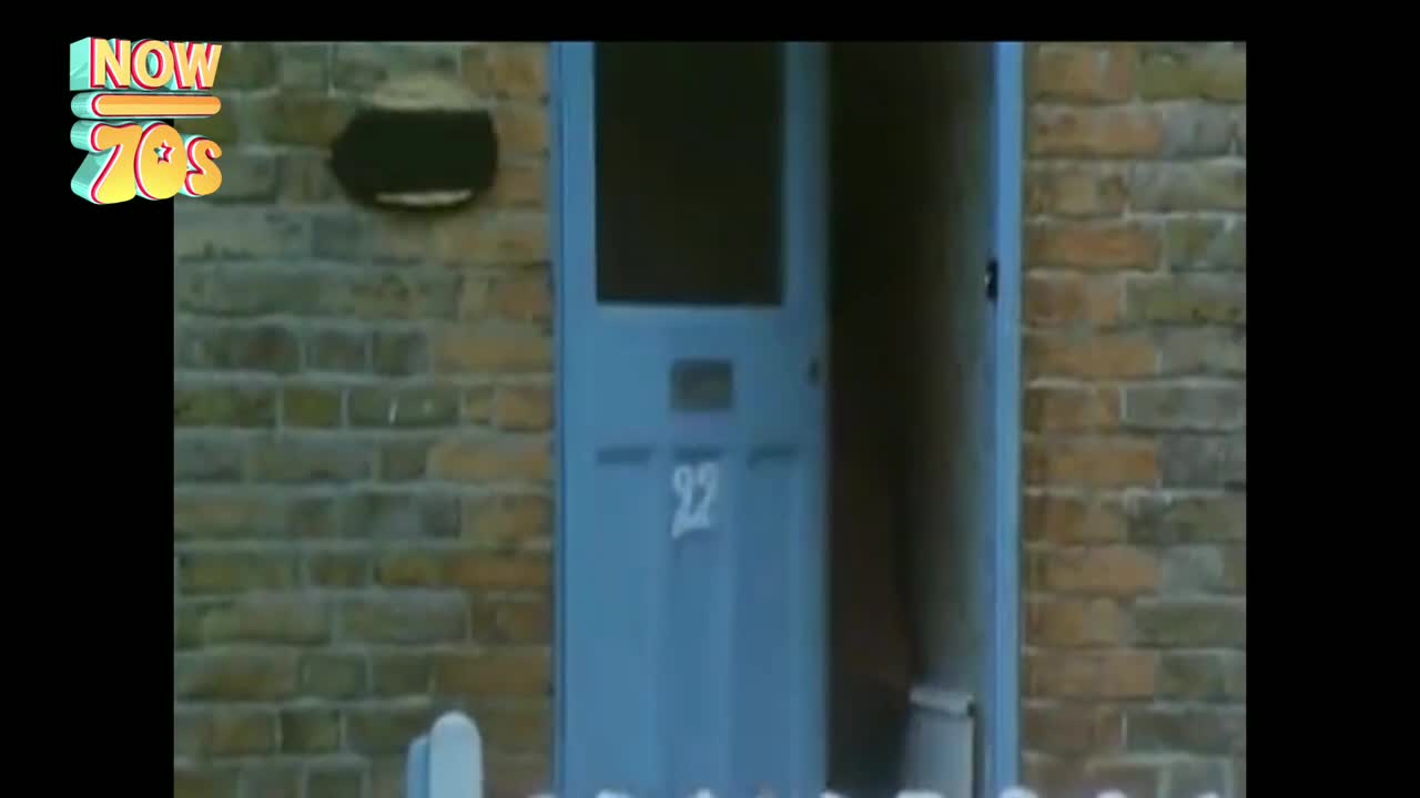 The blue front door of number 22 is ajar, revealing a glimpse of the interior. A small bin sits just inside the doorway.
