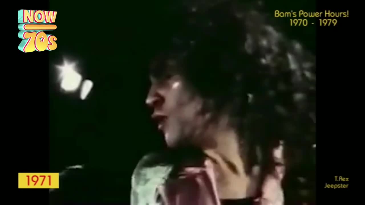 The singer is leaning into the microphone, his dark hair swirling around his face. Stage lights reflect off his skin as he belts out a song.
