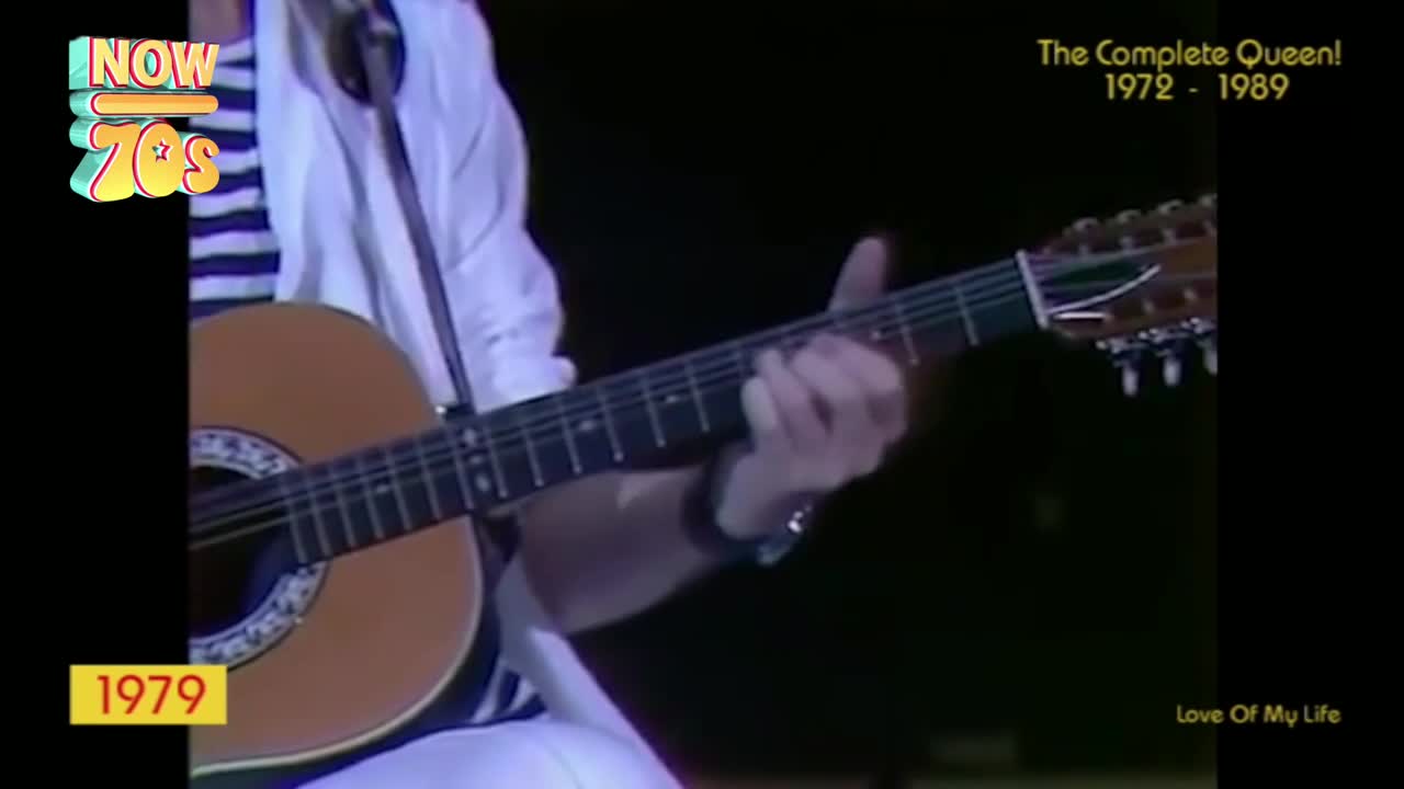 A guitarist's fingers dance across the frets of a twelve-string acoustic. The stage lights catch the wood of the instrument as he strums, the music filling the arena.
