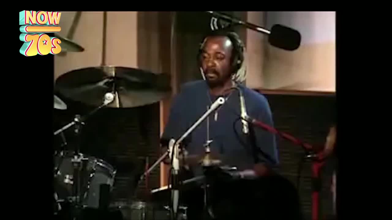 The drummer, wearing headphones, is focused on the kit, his sticks poised. A cymbal shimmers as he hits it, a sharp, metallic sound filling the room.
The drummer, wearing headphones, is focused on the kit, his sticks poised. A cymbal shimmers as he hits it, a sharp, metallic sound filling the room.