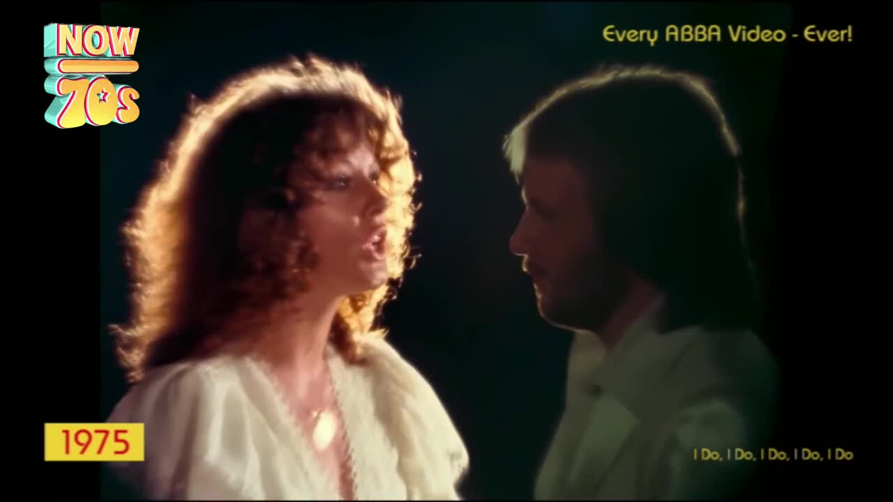 A woman with big, curly hair sings, her face lit from behind. Across from her, a man with a beard looks on, the words "I Do, I Do, I Do" appearing at the bottom.
A woman with big, curly hair sings, her face lit from behind. Across from her, a man with a beard looks on, the words "I Do, I Do, I Do" appearing at the bottom.