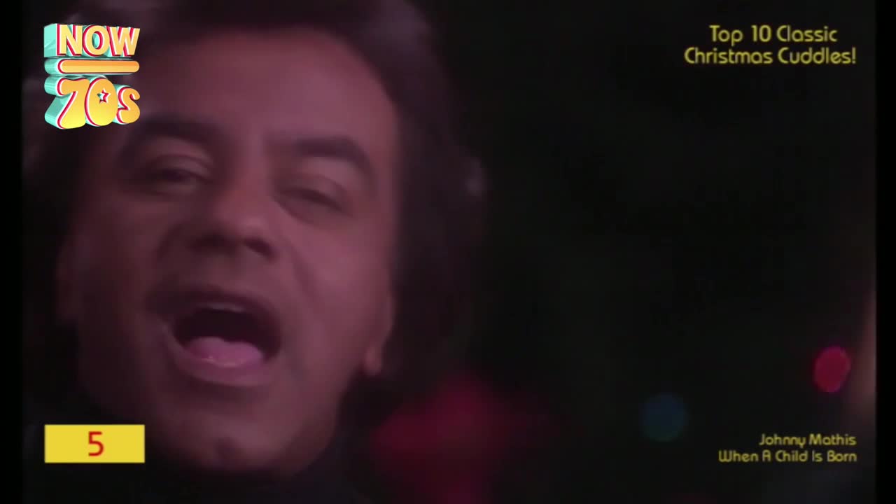 The singer's face fills the screen, his mouth wide open as he belts out a song. It's a Christmas special, and the graphics show it's number five on the countdown.
The singer's face fills the screen, his mouth wide open as he belts out a song. It's a Christmas special, and the graphics show it's number five on the countdown.