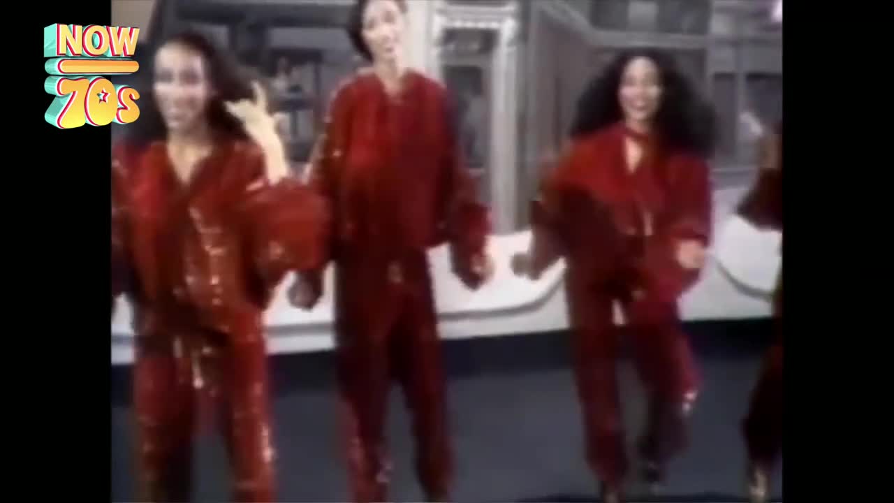 Four women in matching red jumpsuits are dancing, their arms and hair moving with the music. They're all smiling, and the light catches the sheen of their outfits.
Four women in matching red jumpsuits are dancing, their arms and hair moving with the music. They're all smiling, and the light catches the sheen of their outfits.