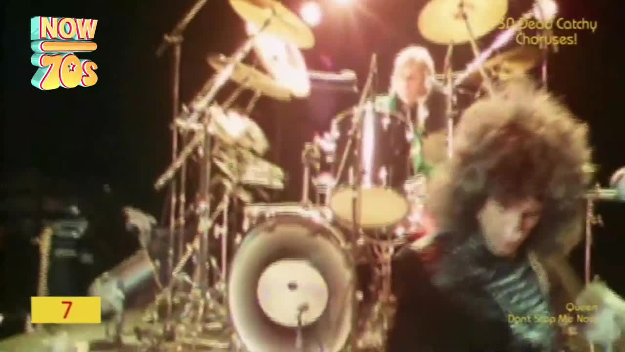 A drummer with a massive afro pounds out a rhythm on a gleaming kit. Behind him, a blonde-haired singer in a leather jacket leans into the microphone.