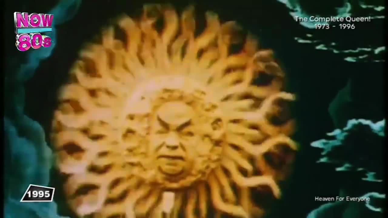 A sun-like face with radiating tendrils fills the screen, its features carved in stone. The "Now 80s" logo and the year 1995 are visible, and a title card for a Queen compilation appears.
