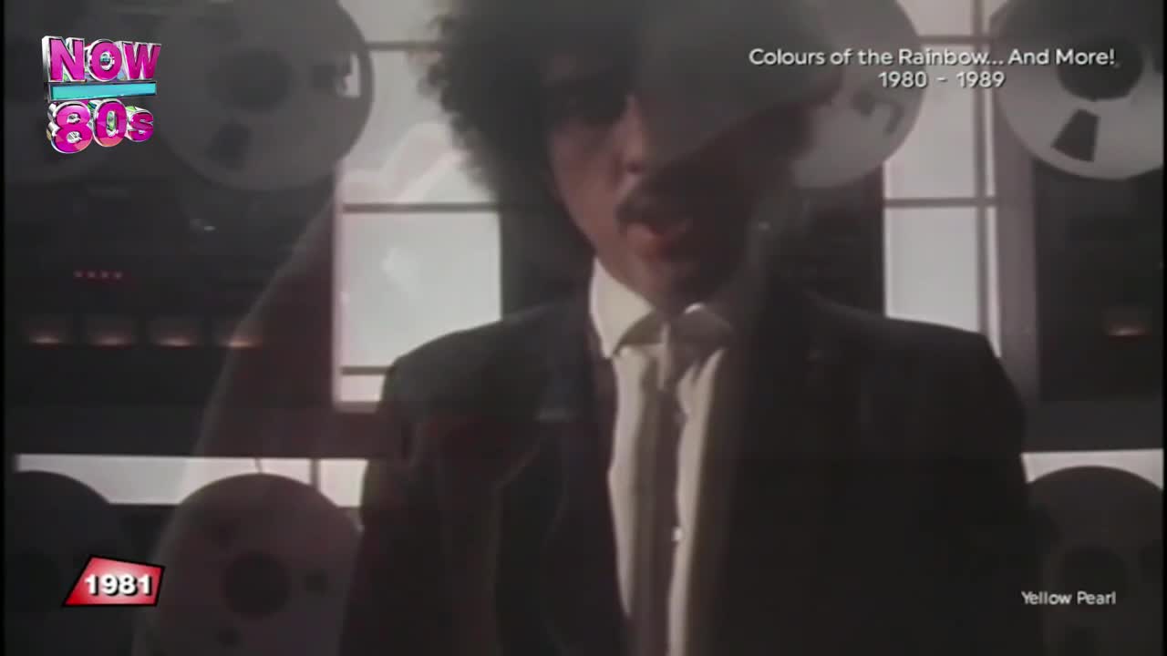 The man in the suit, with his afro, is speaking. Behind him, the reel-to-reel tapes are slowly turning, a familiar sight from British music television in the early 80s.
