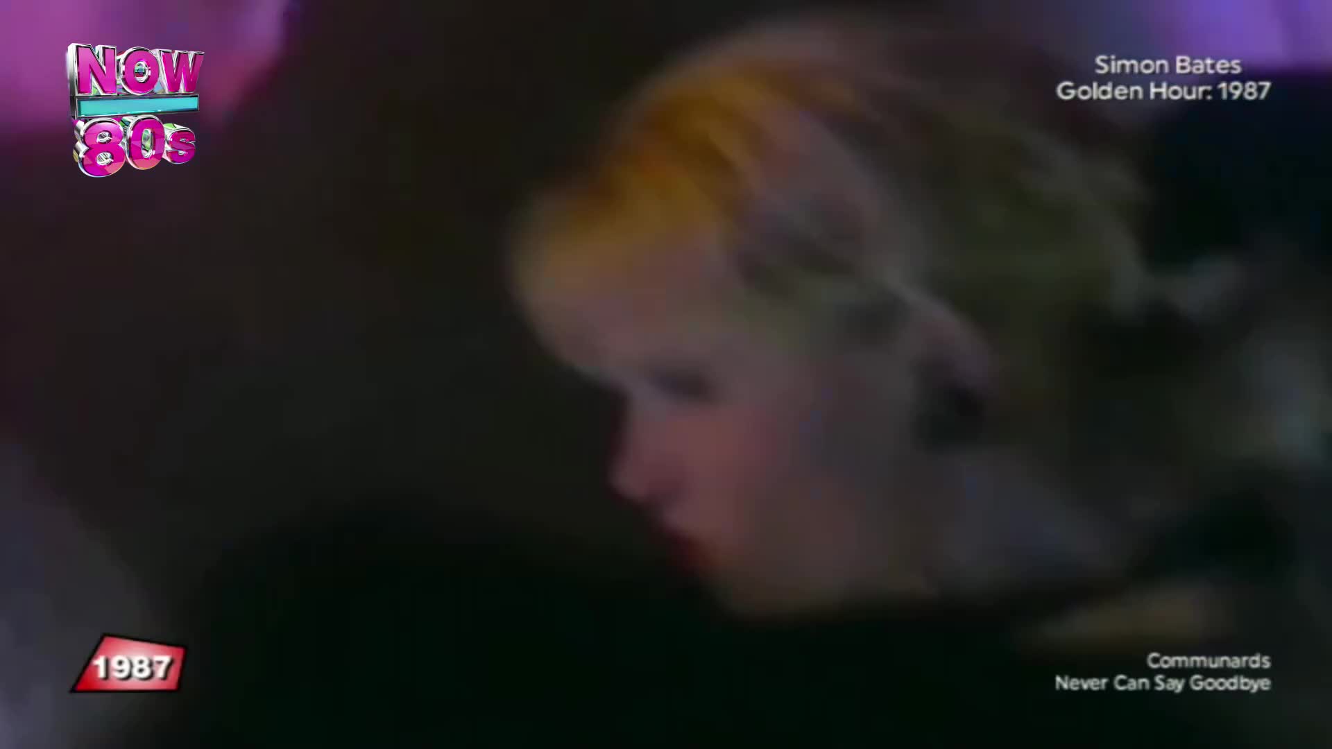 A woman's face is slightly out of focus, her blonde hair and profile visible against a dark background. The "Now 80s" logo glows in the corner, a reminder of the music video's era.
