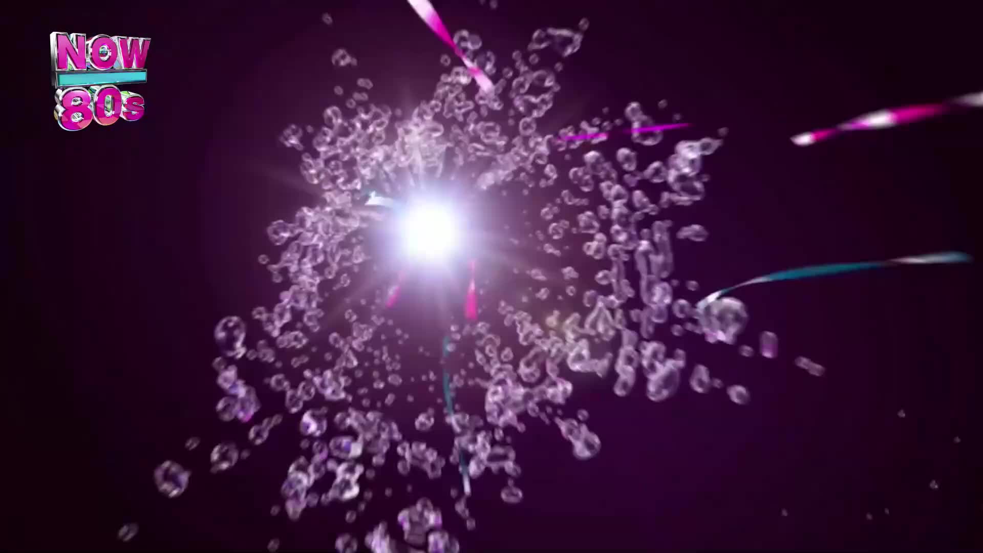 A bright light explodes at the center, surrounded by a cluster of translucent droplets. Streaks of pink and blue shoot out from the light, as if bursting forth from the center.
