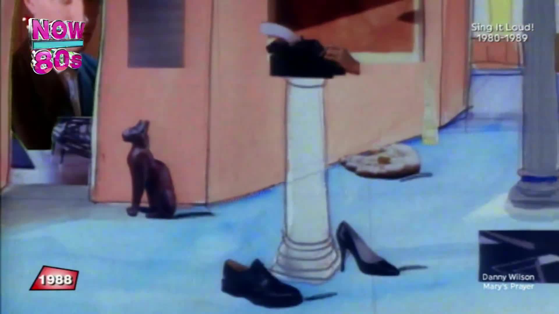 A brown cat statue sits on the floor, its head raised. Next to it, a pair of men's shoes and a high-heeled shoe are placed on the ground.
