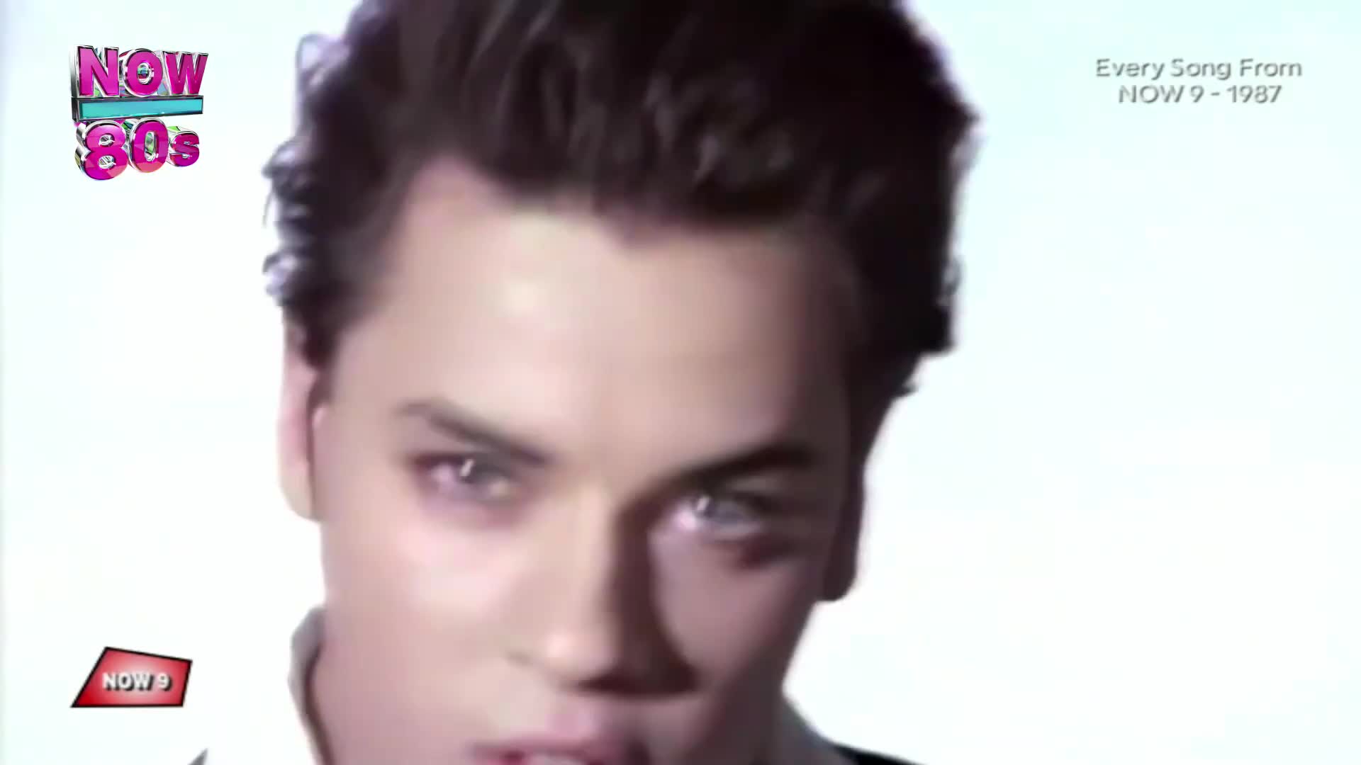 A young man with dark, styled hair stares intensely, his blue eyes piercing. The "NOW 80s" logo, a vibrant pink and turquoise, sits in the corner, hinting at a compilation from that era.