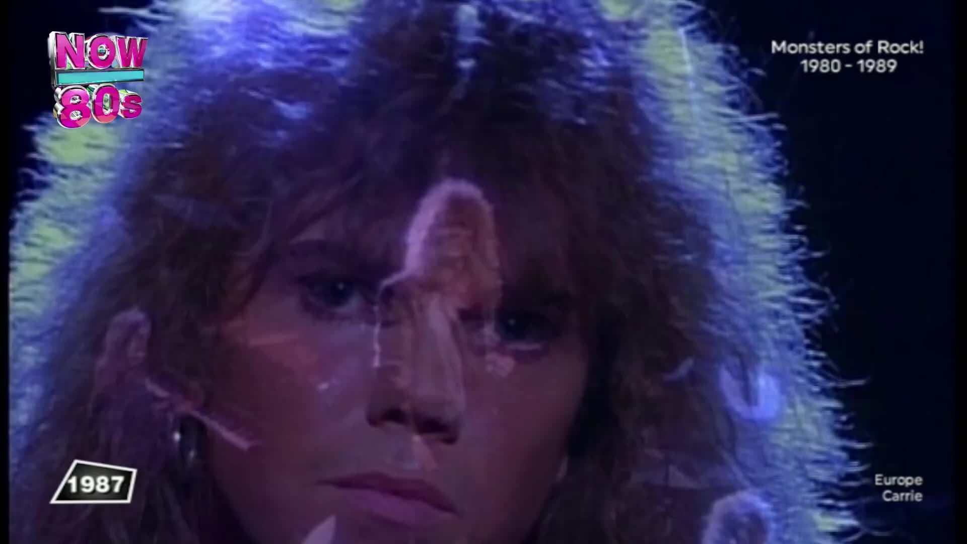 The stage lights catch the singer's long, blonde hair as a ghostly image of a woman flickers across his face. This is from a Monsters of Rock performance in 1987.