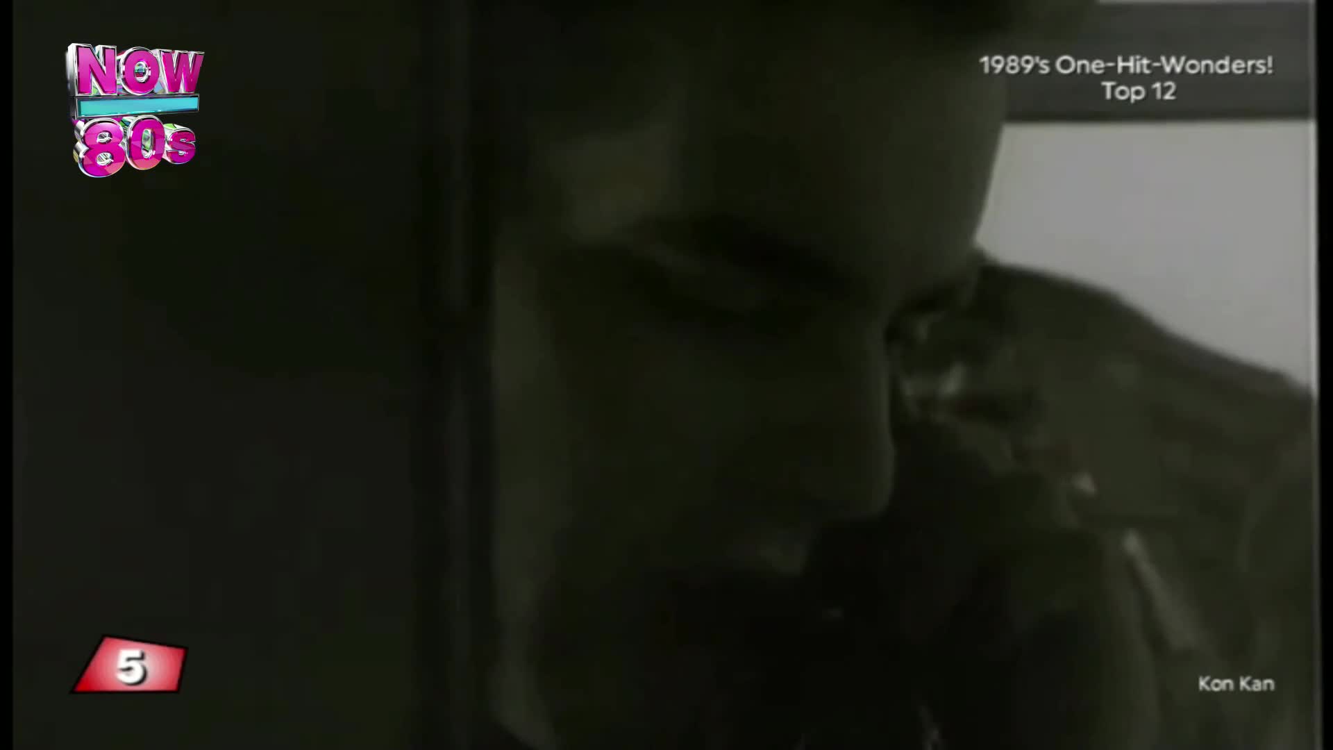 A man's face is close to the camera, his expression obscured by shadow. The "Now 80s" logo appears in the top left corner.