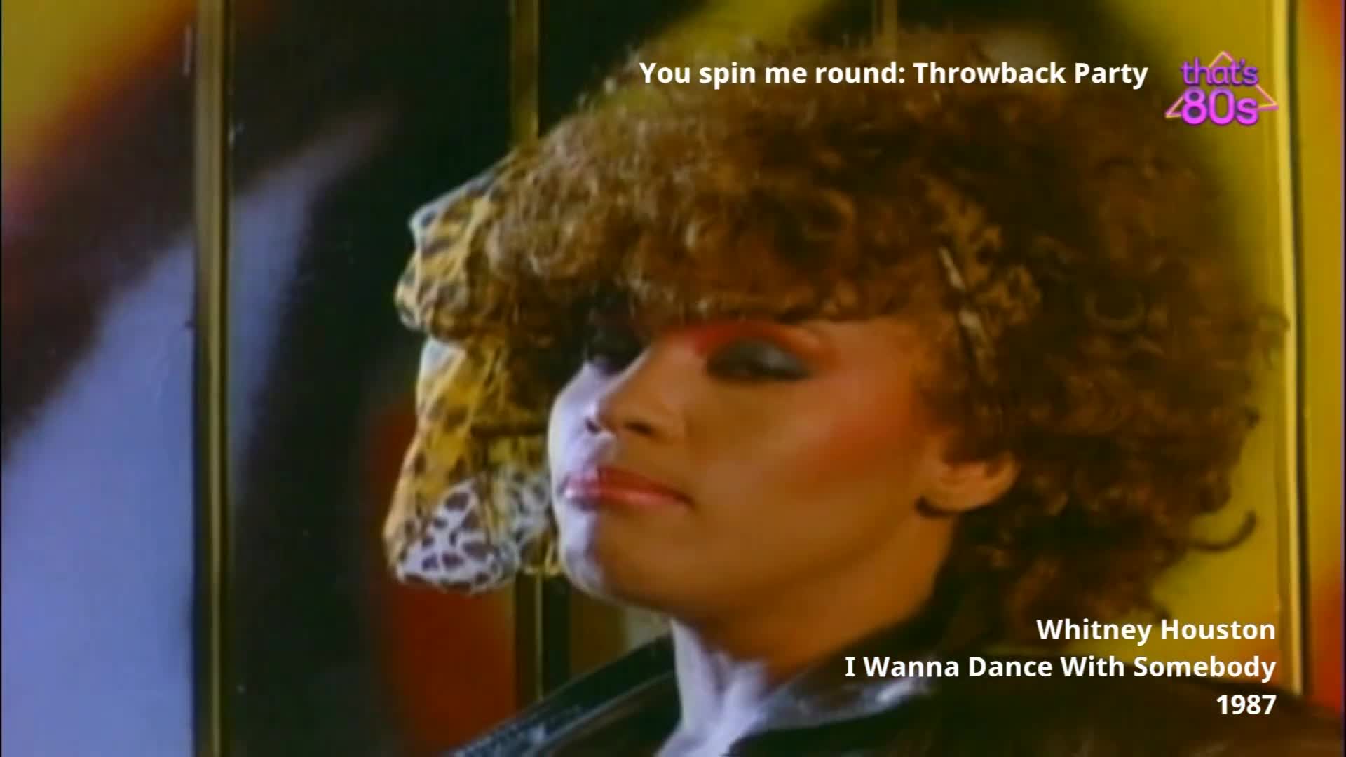 A woman with a large, curly hairstyle and dramatic makeup tilts her head slightly. Her leopard-print scarf adds a splash of pattern to the scene.