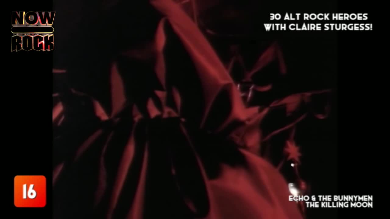 Dark red cloaks swirl in the dim light, their folds creating shadowy shapes. The NOW Rock logo and the "16" rating are visible, suggesting a music video.
