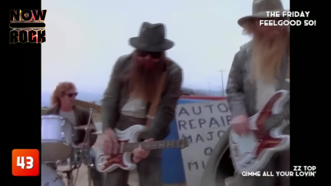 The band, ZZ Top, is playing in front of a faded auto repair sign. The drummer keeps the beat while the guitarists, in matching outfits, strum their instruments.
