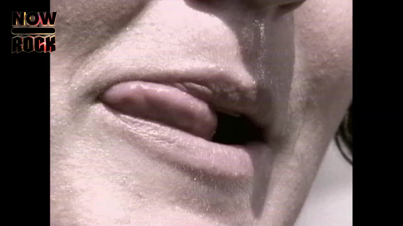 The person's mouth is open, and their tongue is extended.  Sweat glistens on their skin, and the darkness of the mouth is visible.
