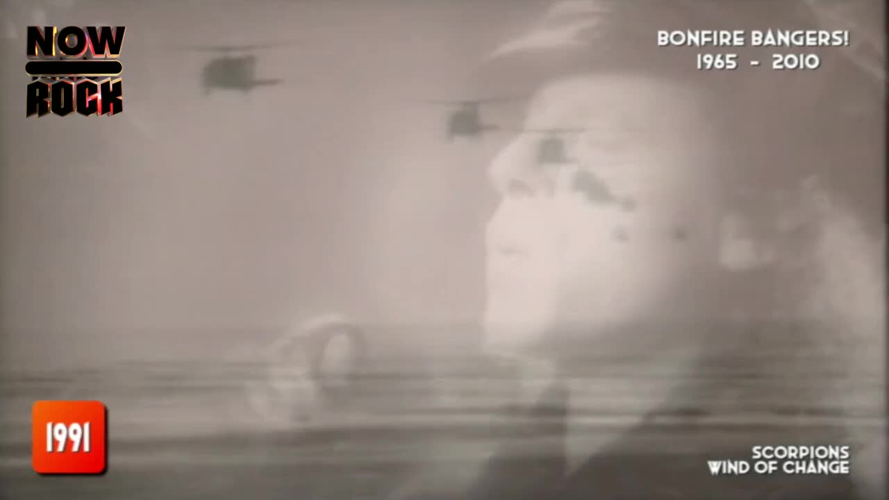 The singer's face is superimposed over a hazy, water-like background, with helicopters fading in the distance. The NOW Rock logo and "Bonfire Bangers!" text frame the scene, hinting at a music video from the early nineties.
