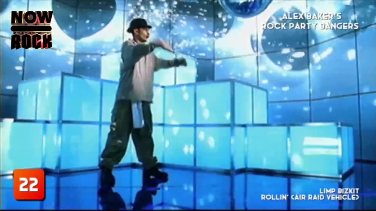 A man in a backwards cap and baggy pants is dancing on a stage made of glowing blue blocks. The NOW Rock logo and "Alex Baker's Rock Party Bangers" are visible on the screen.
