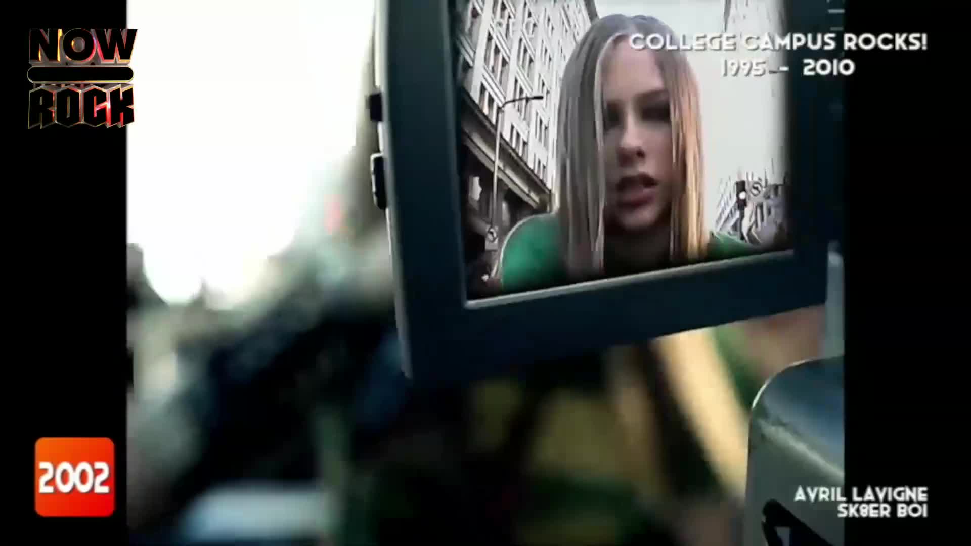 A screen displays Avril Lavigne, her face framed by long blonde hair, looking surprised. The NOW Rock logo and the year 2002 flash on the screen's edge.
A screen displays Avril Lavigne, her face framed by long blonde hair, looking surprised. The NOW Rock logo and the year 2002 flash on the screen's edge.