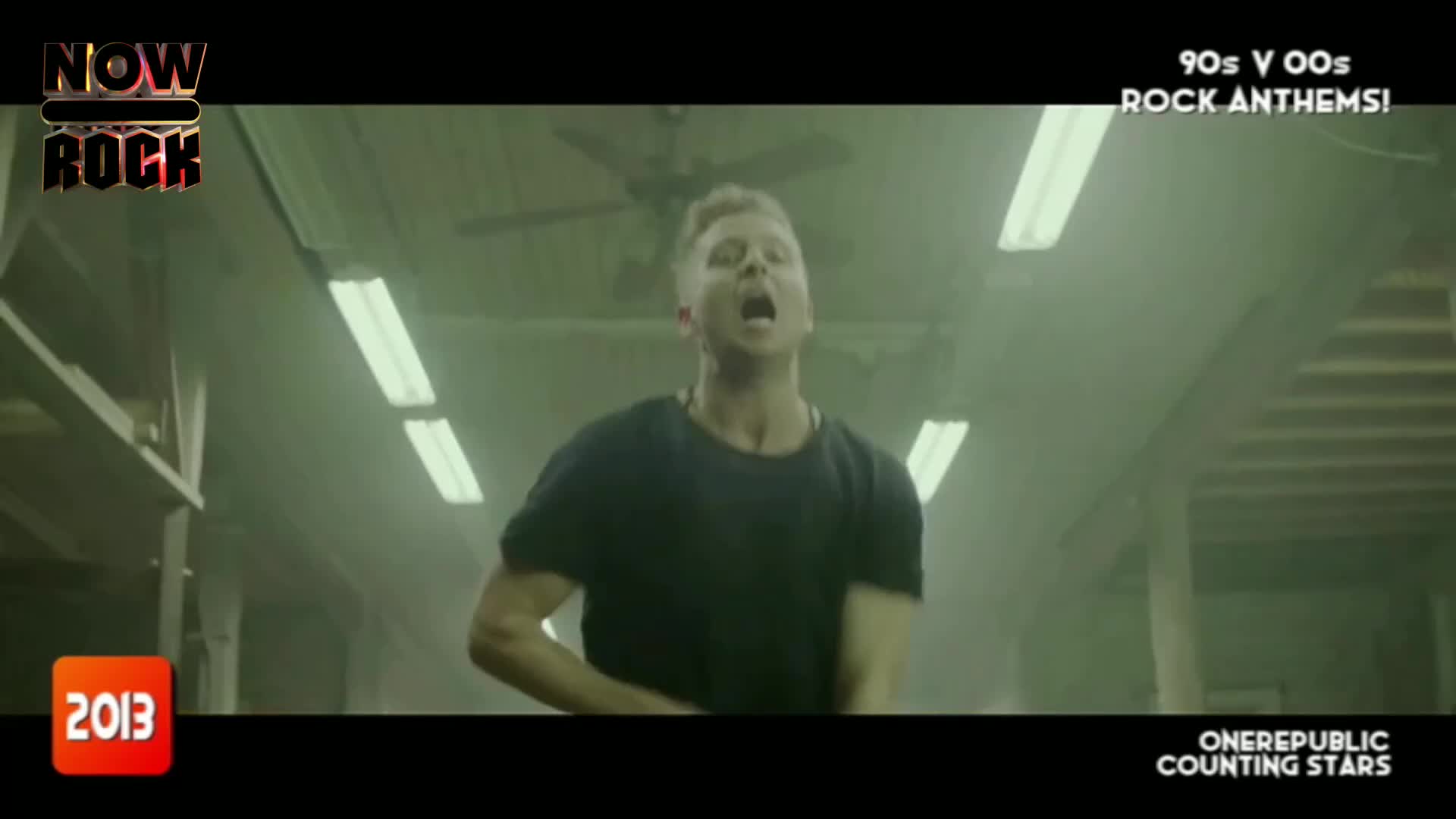 The singer, in a black t-shirt, is belting out a song, his mouth wide open. He's in a dimly lit, industrial space with fluorescent lights overhead.
The singer, in a black t-shirt, is belting out a song, his mouth wide open. He's in a dimly lit, industrial space with fluorescent lights overhead.