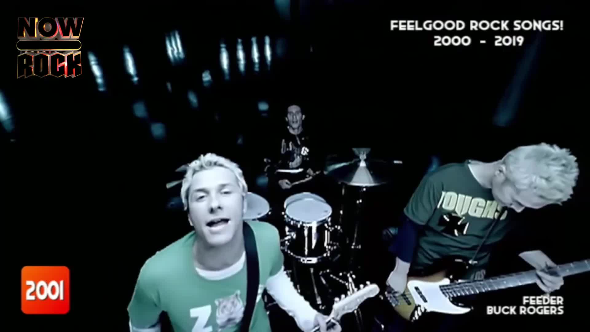 The singer, with bleached hair, is belting into the camera, while the guitarist and drummer keep the beat. The band, Feeder, is performing on a dark stage, with a NOW Rock logo in the corner.
