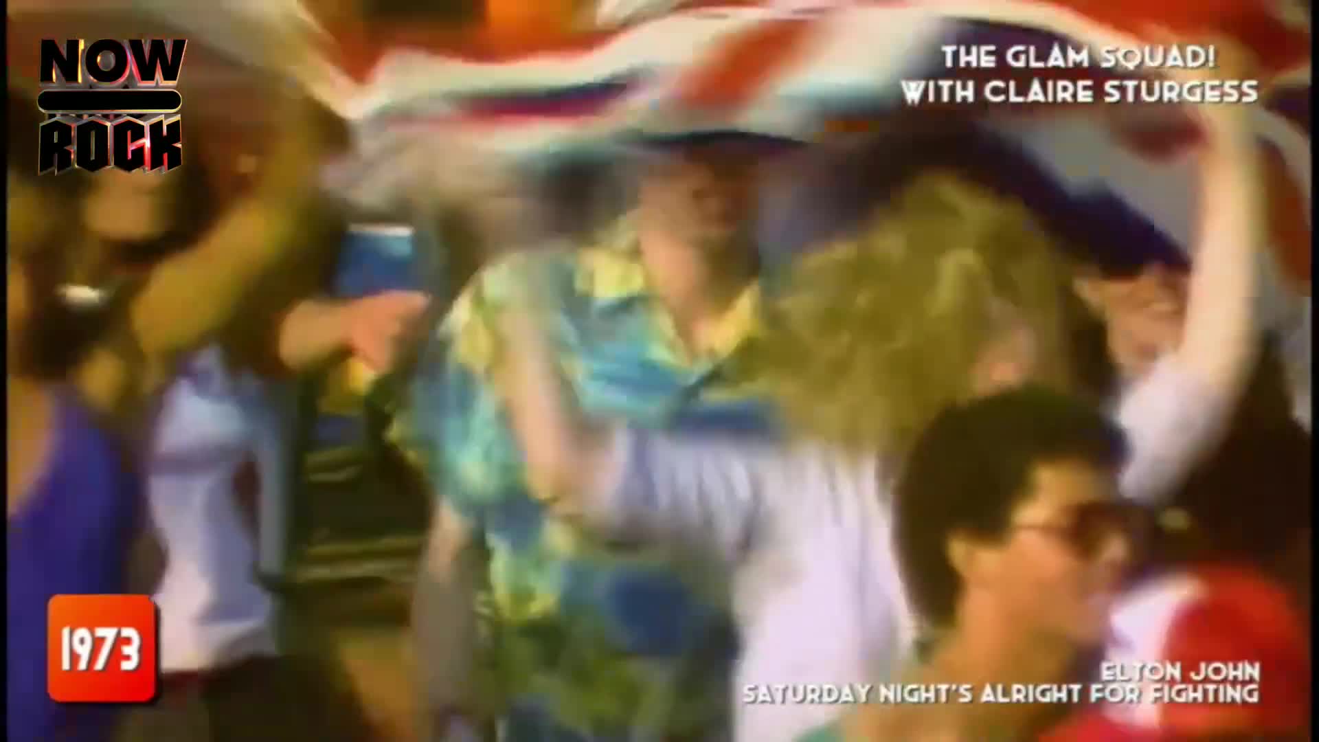 The crowd surges forward, a sea of faces and waving arms beneath a Union Jack. A man in a bright, patterned shirt grins as he's jostled by the energy of the moment.