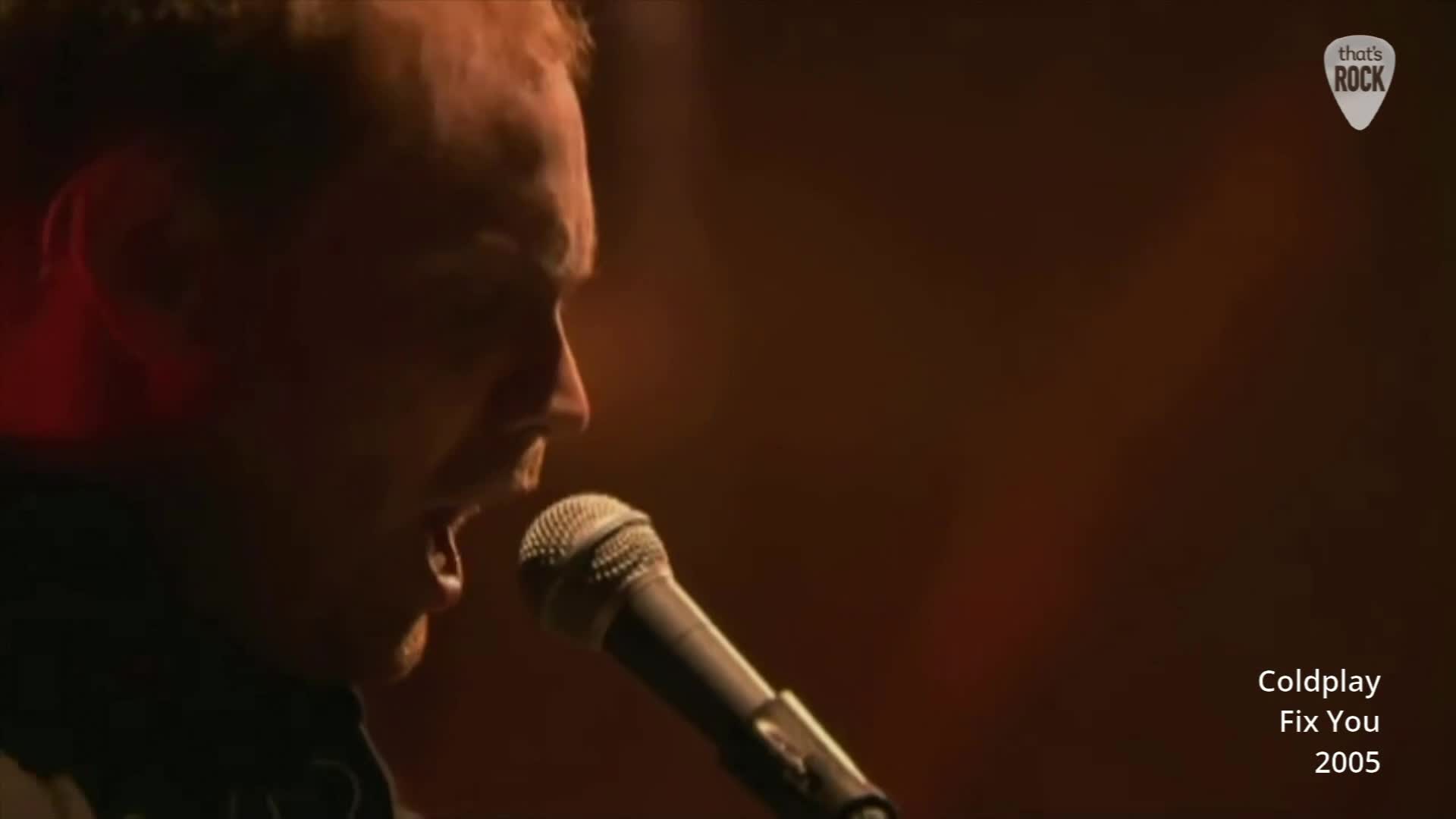 Chris Martin belts out lyrics into a microphone, his face illuminated by a warm stage light. The British band Coldplay is performing "Fix You" live in 2005. Chris Martin belts out lyrics into a microphone, his face illuminated by a warm stage light. The British band Coldplay is performing "Fix You" live in 2005.