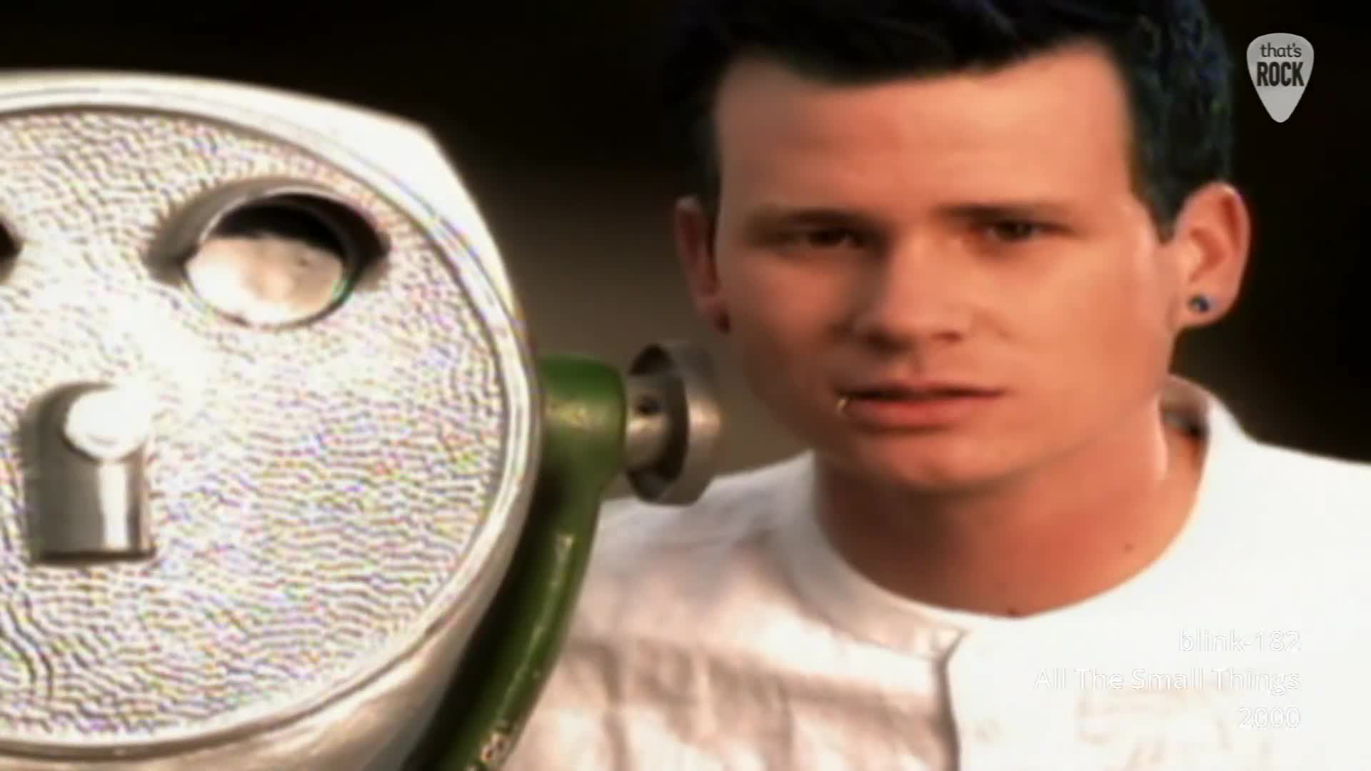 A man with blue-dyed hair and a lip ring stares intently past a large, coin-operated viewer. The weathered metal of the viewer, a common sight on British coastlines, reflects the muted light. A man with blue-dyed hair and a lip ring stares intently past a large, coin-operated viewer. The weathered metal of the viewer, a common sight on British coastlines, reflects the muted light.