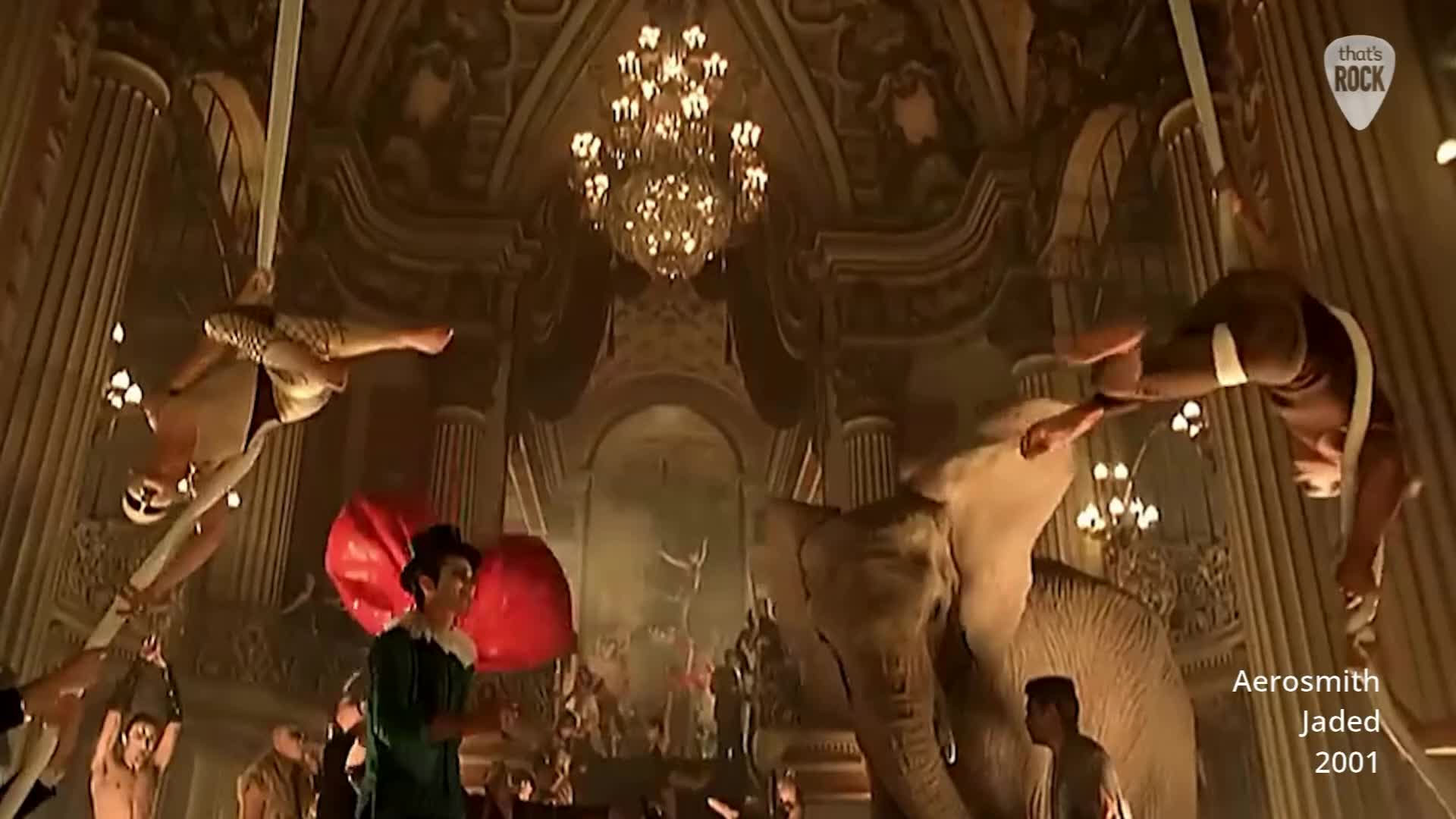 An elephant stands centre stage as aerialists perform above. A man in a green costume juggles large red balls. An elephant stands centre stage as aerialists perform above. A man in a green costume juggles large red balls.