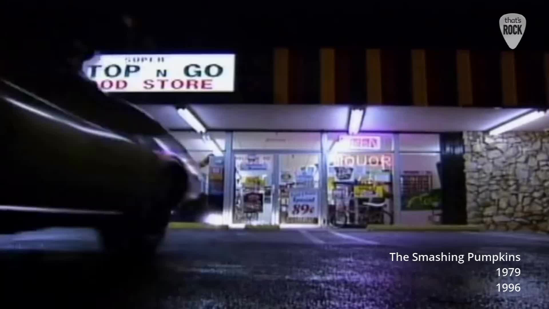 A dark car speeds past a brightly lit convenience store. The store's sign reads "SUPER TOP N GO FOOD STORE" in bold letters. A dark car speeds past a brightly lit convenience store. The store's sign reads "SUPER TOP N GO FOOD STORE" in bold letters.