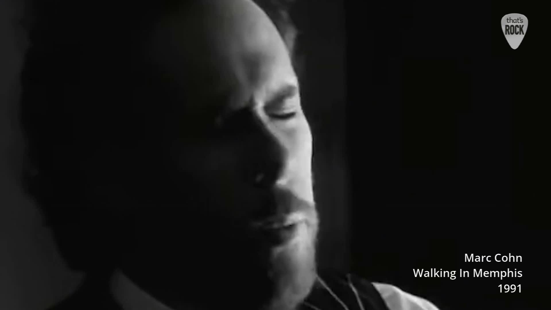 A man's face, lit from the side, is captured in a close-up. He has his eyes closed, and a faint smile plays on his lips.