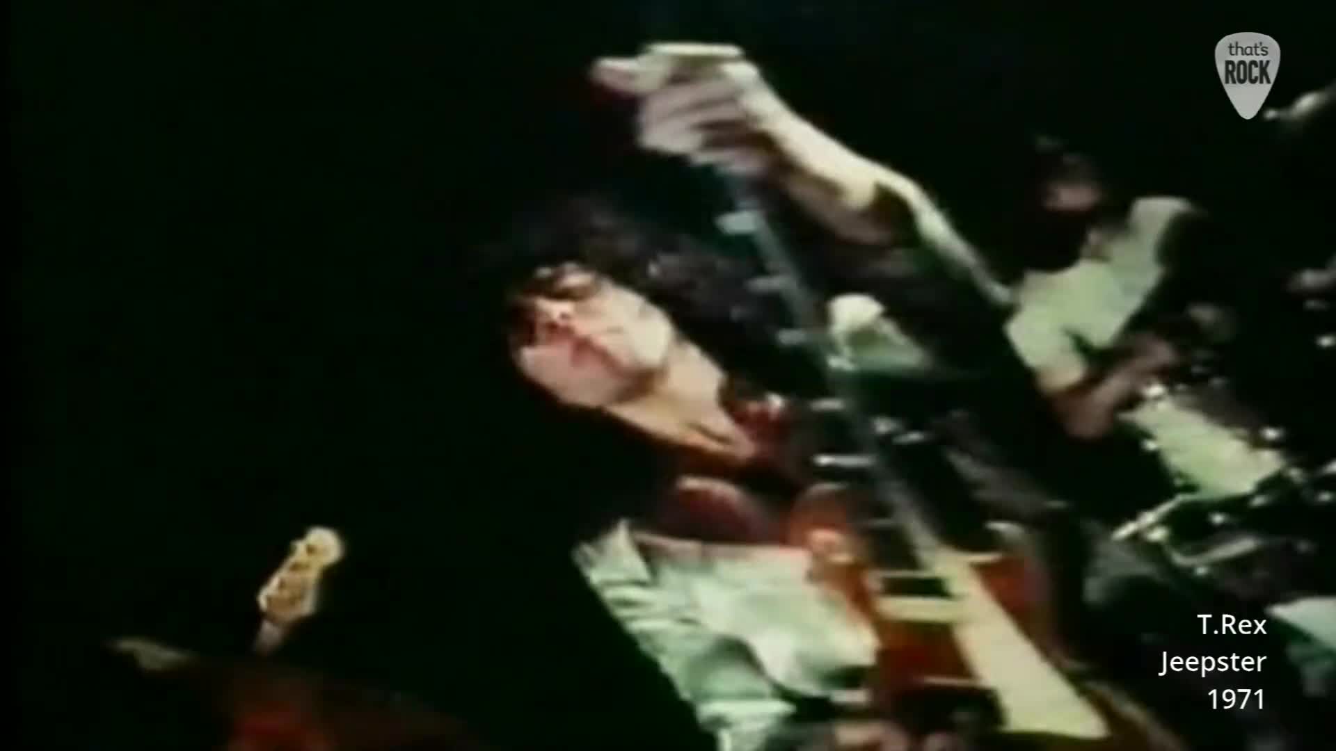 Marc Bolan's hand grips his guitar neck as he leans into the microphone. The band is in full swing, a live performance from 1971.