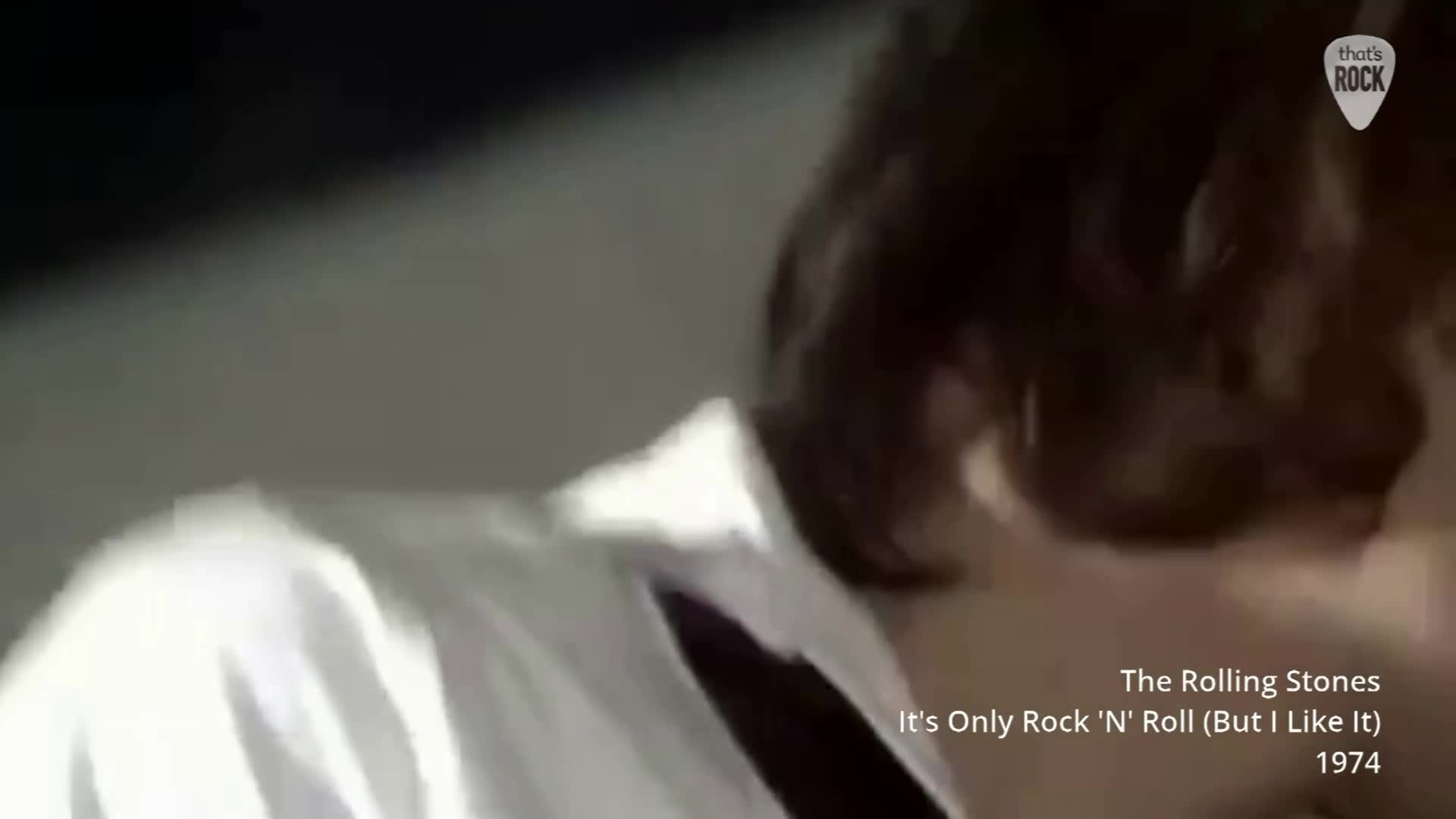 Mick Jagger leans in, his white shirt collar stark against his dark hair. He's lost in the music, a familiar sight from a 1974 performance.