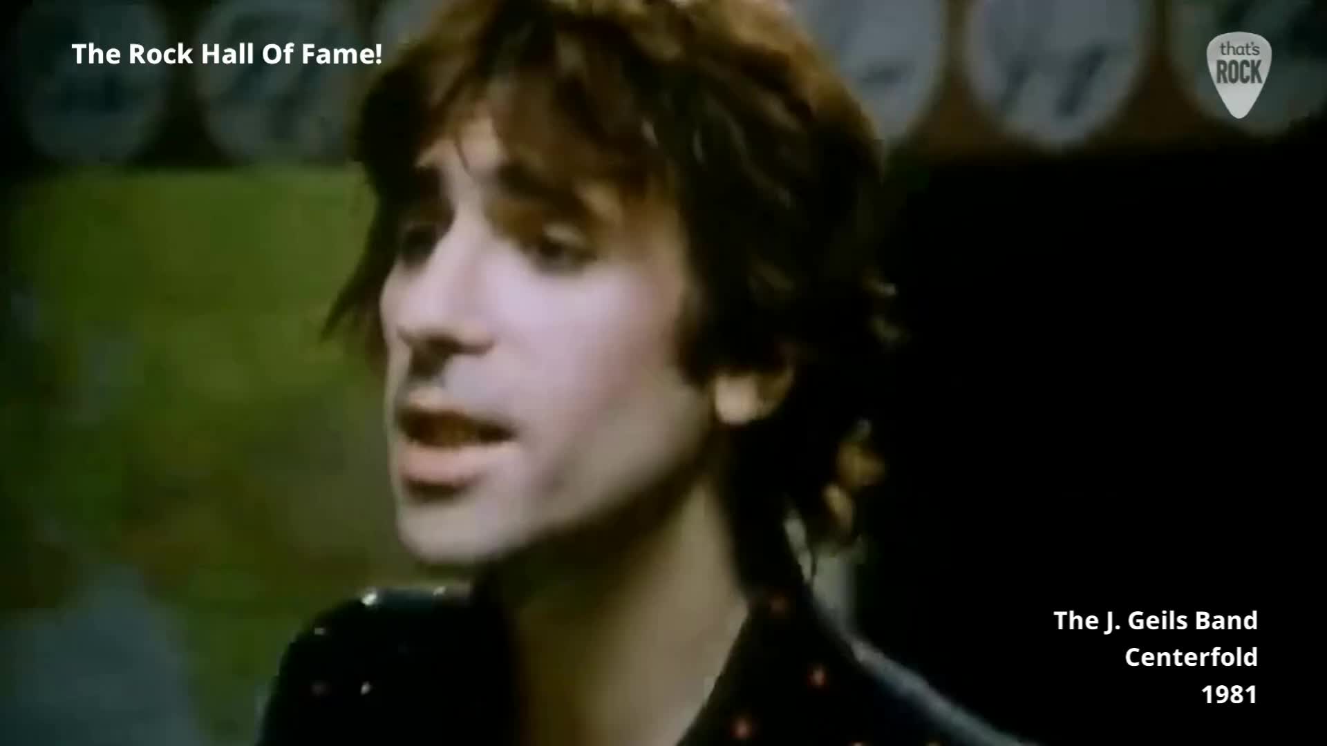 The J. Geils Band's Peter Wolf is captured mid-song, his mouth open as he belts out lyrics. The grainy footage, likely from a 1981 music video, shows him with his signature tousled hair and a patterned shirt.