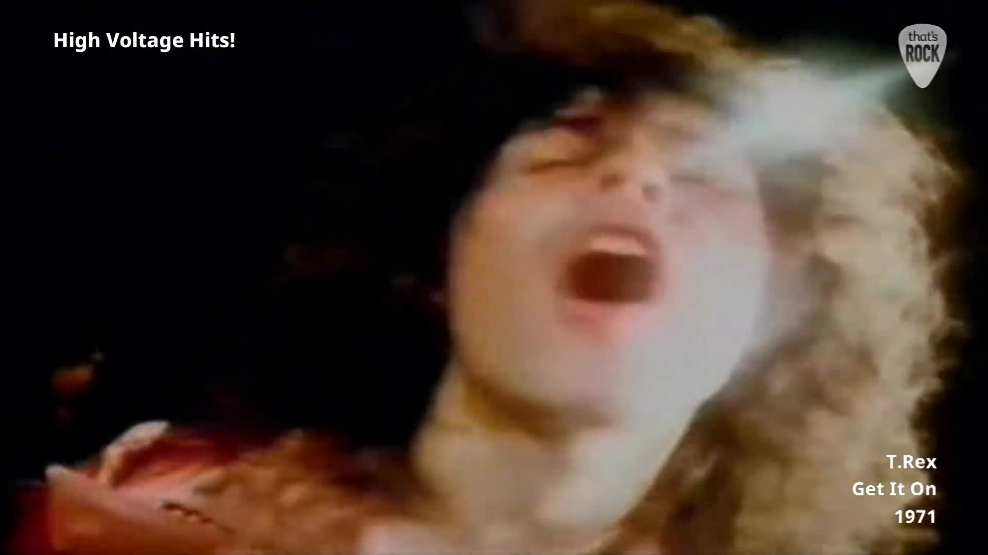 Marc Bolan's face is contorted in a primal scream, his mouth wide open. A bright light flashes across his forehead, illuminating his wild, curly hair.
