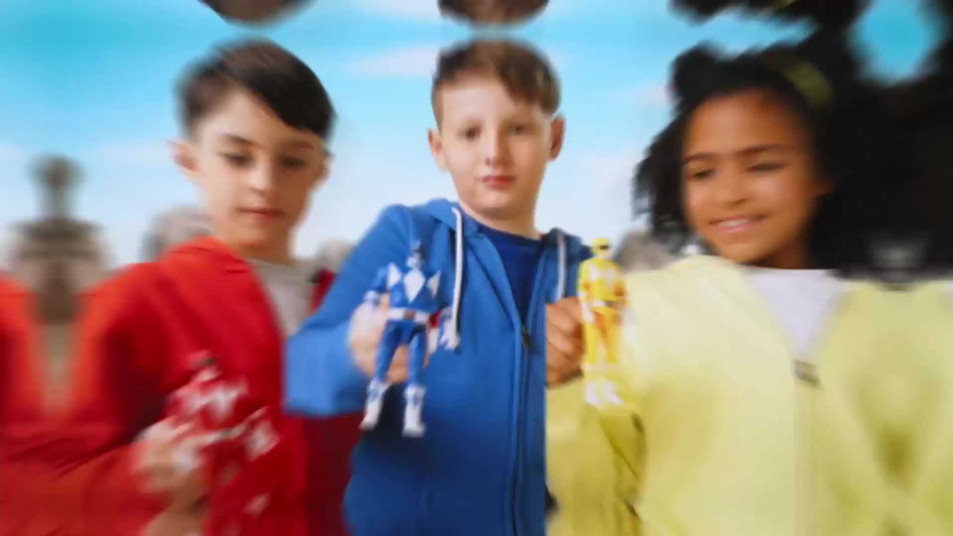 Kids, each holding a Power Ranger figure, are moving toward the camera. The boy in the blue hoodie is centered, with a blue Ranger in his hand.
