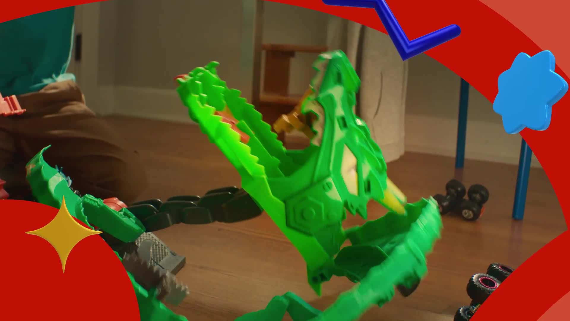 A green, plastic snake's mouth is wide open, ready to "eat" a small toy car. The track curves around the floor, with a child's legs visible in the background.
