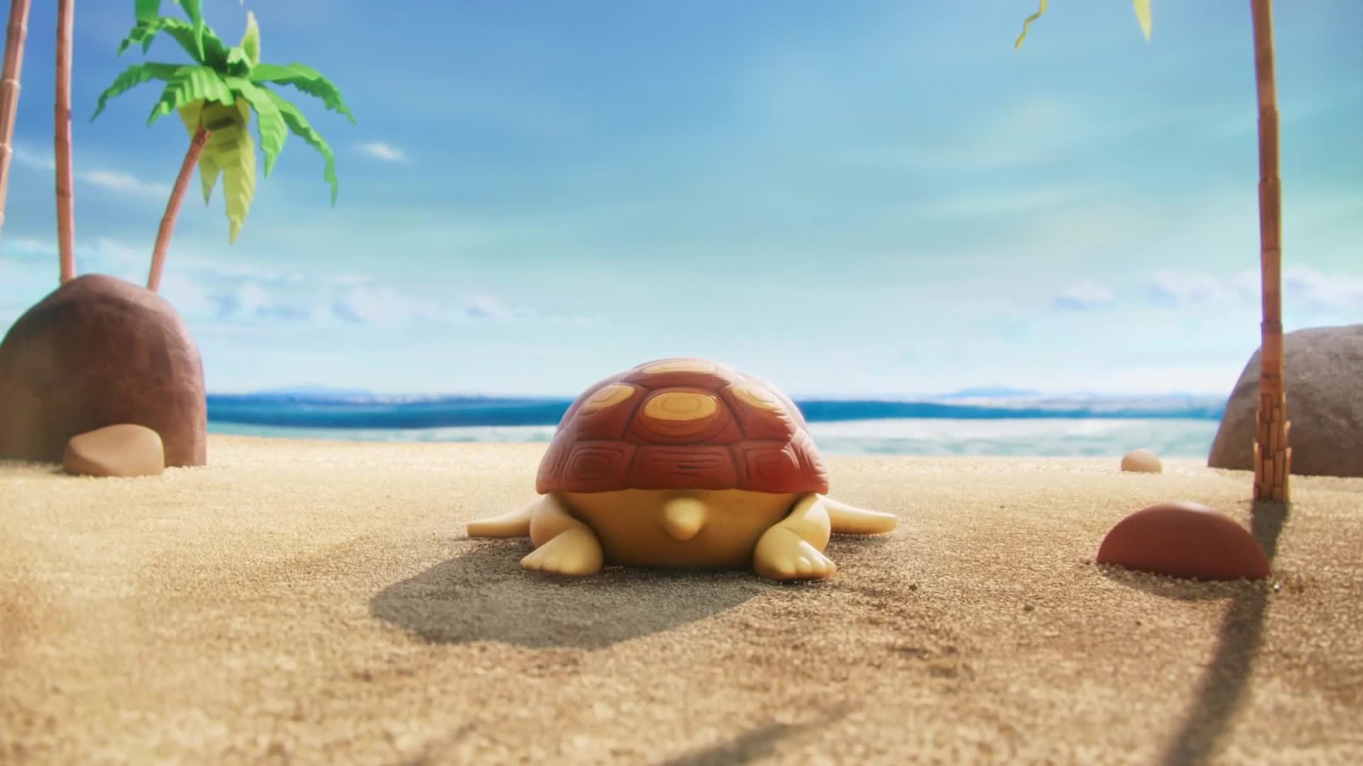 A toy turtle rests on the sand, its shell a mix of brown and yellow. Palm trees and the ocean provide a backdrop to the scene.
