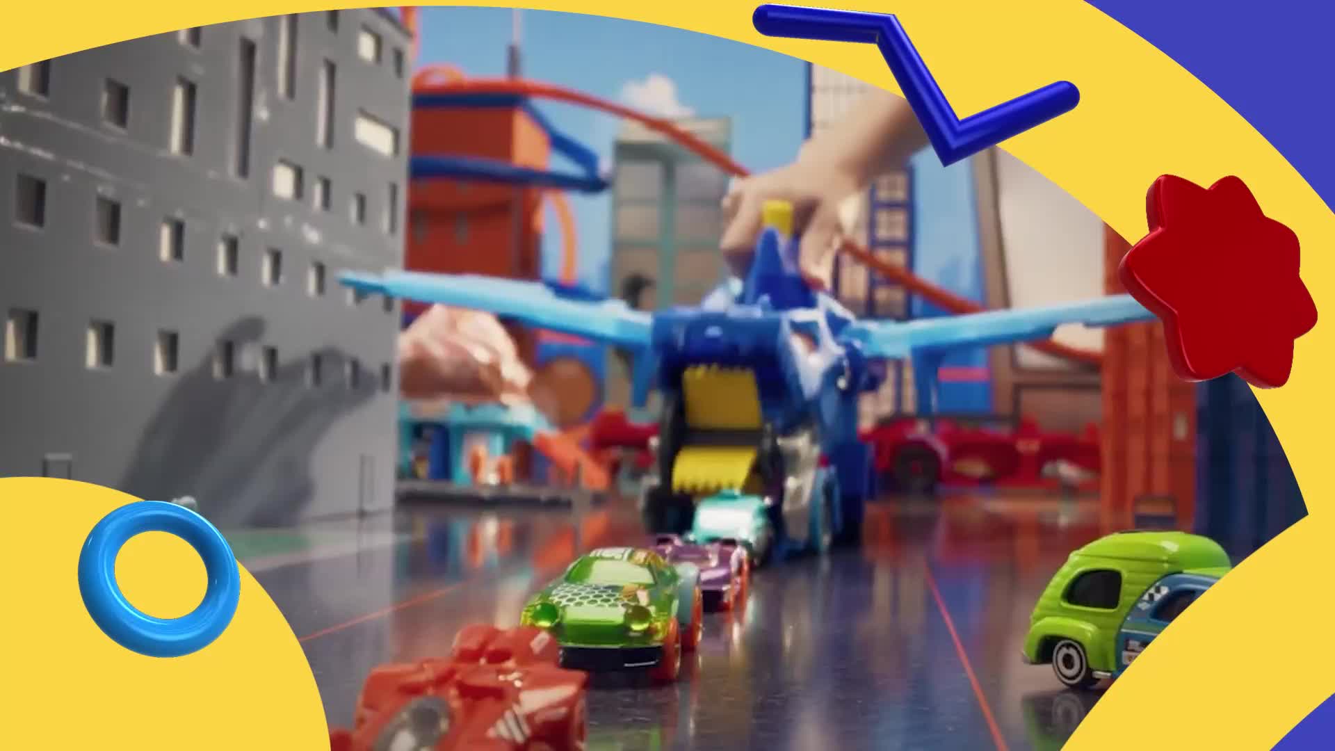 A line of toy cars is moving towards a large blue vehicle with wings. The cars are approaching a cityscape backdrop.

