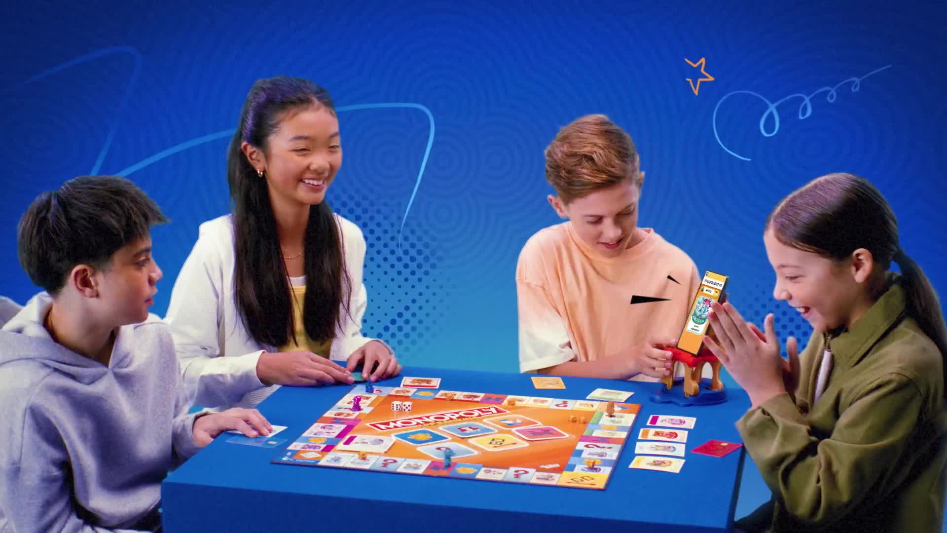Four kids are gathered around a board game, smiling and watching intently. One of them is about to make a move with a small, colorful structure, and the others seem excited.
