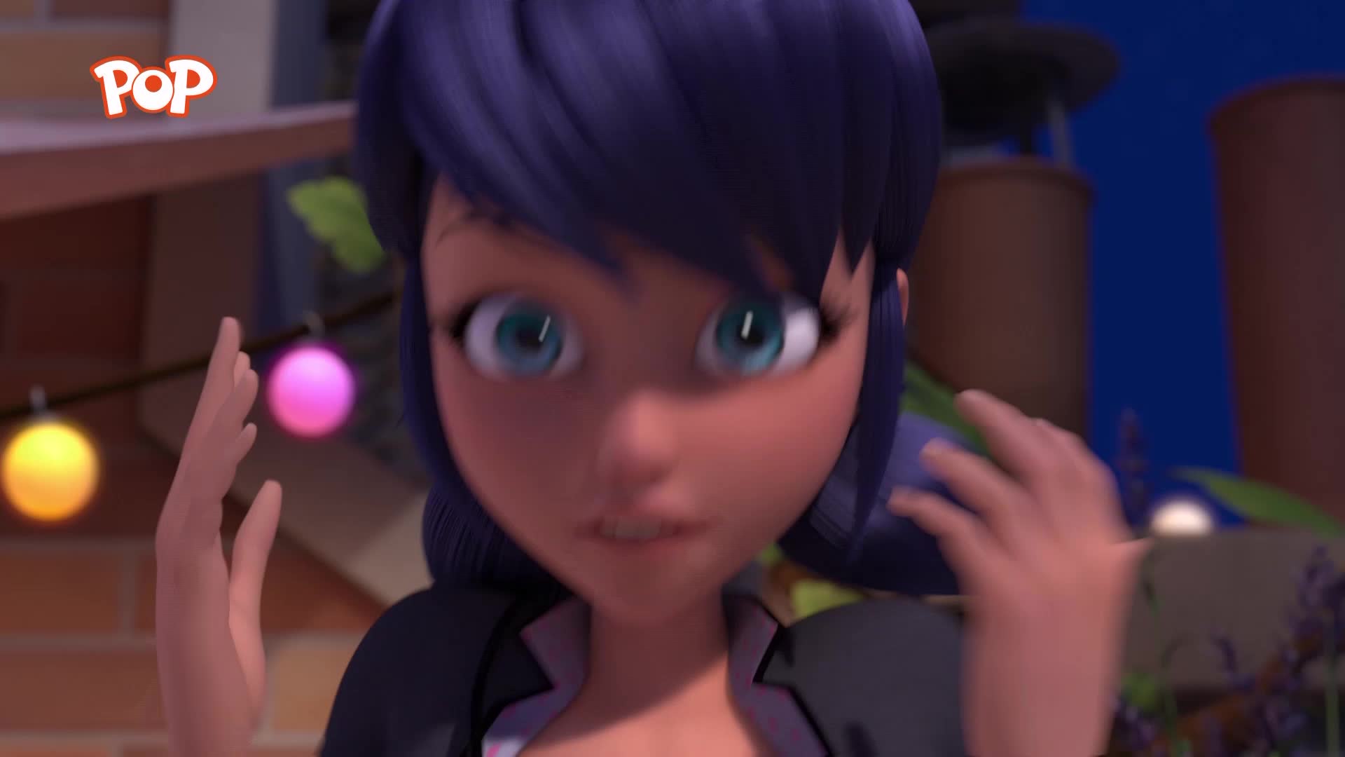 A young woman with bright blue eyes and dark hair is looking directly at me, her hands raised near her face. String lights, one yellow and one pink, hang in the background, suggesting a festive evening.