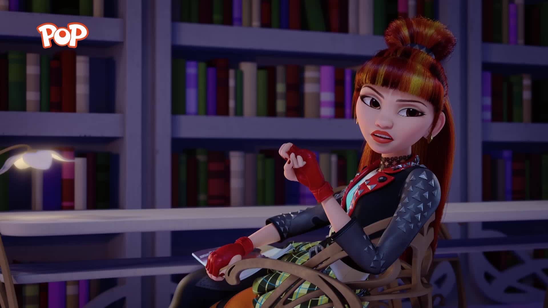 A young woman with fiery red hair, dressed in a punk-inspired outfit, sits in a chair. Bookshelves filled with colourful spines line the background.