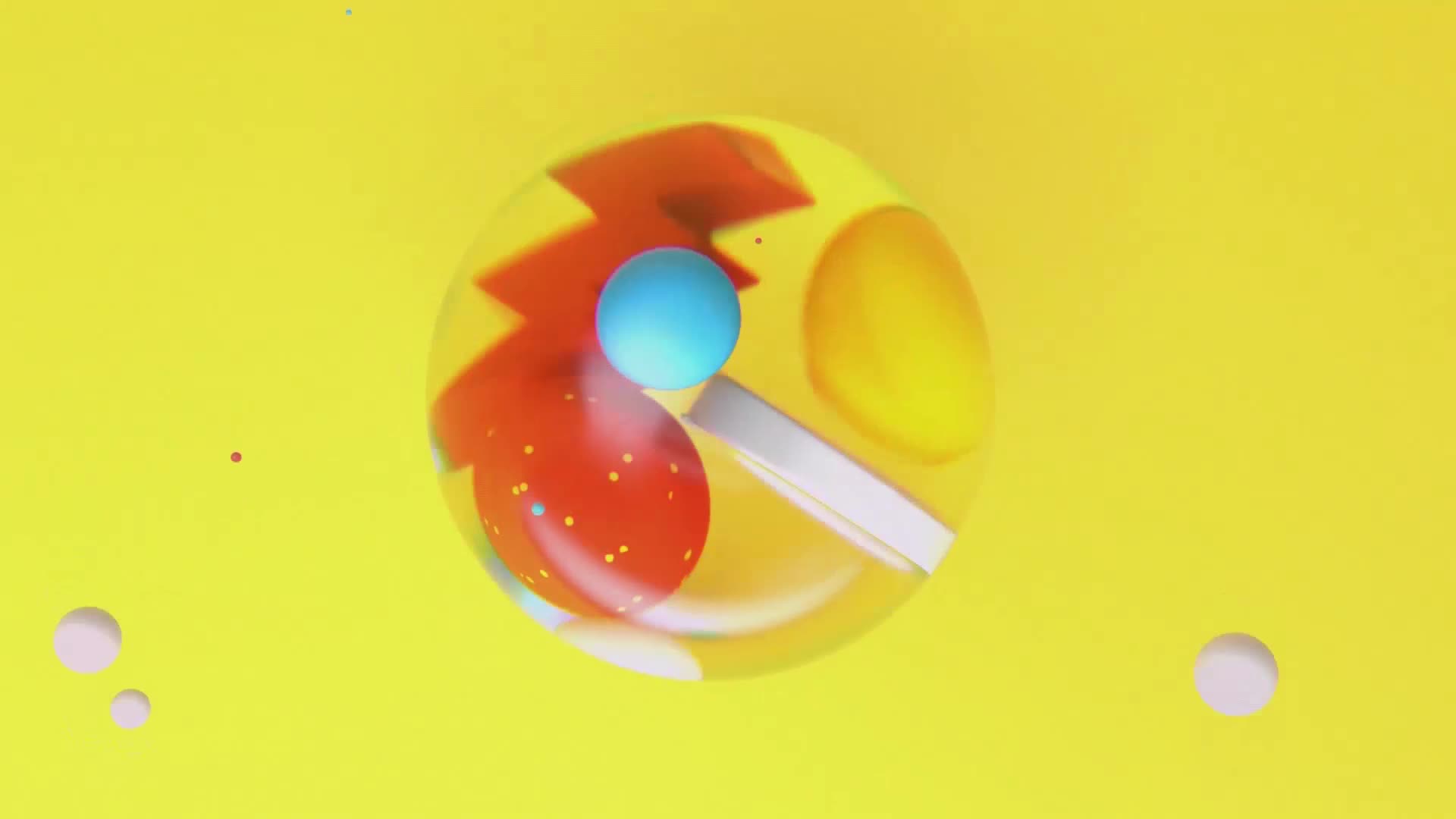 A clear sphere rolls across the bright yellow surface, its contents shifting. Inside, a red, polka-dotted shape with a jagged edge tumbles against a bright blue ball.