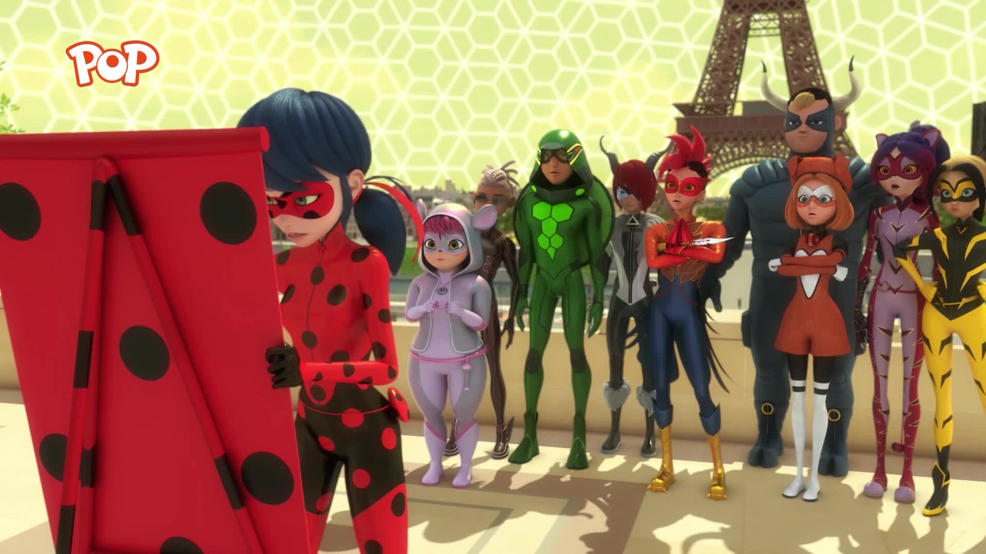 Ladybug stands with a large red and black spotted banner. A diverse group of caped figures stands behind her, facing the Eiffel Tower.